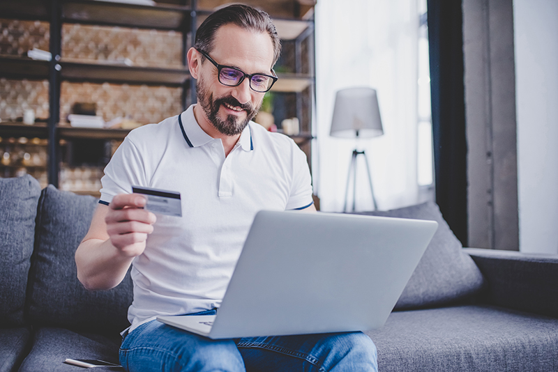 A man practicing safe online shopping using his credit card on his laptop