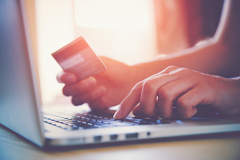 Person shopping online using a laptop and holding their credit card.